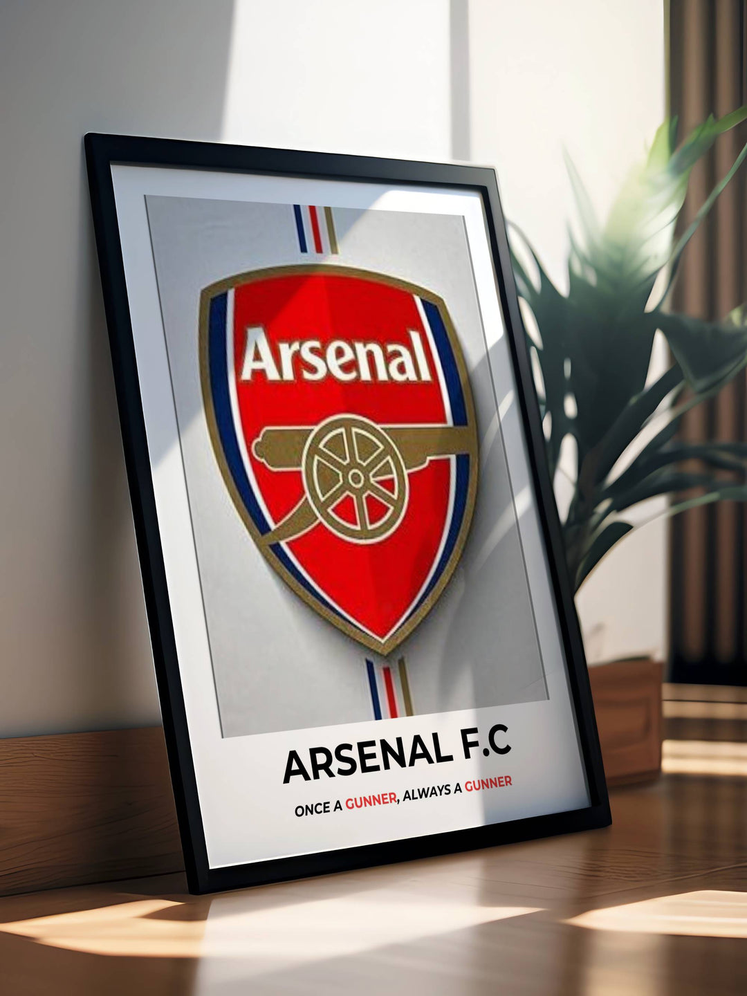 Framed Arsenal F.C. poster on a table with a plant in the background