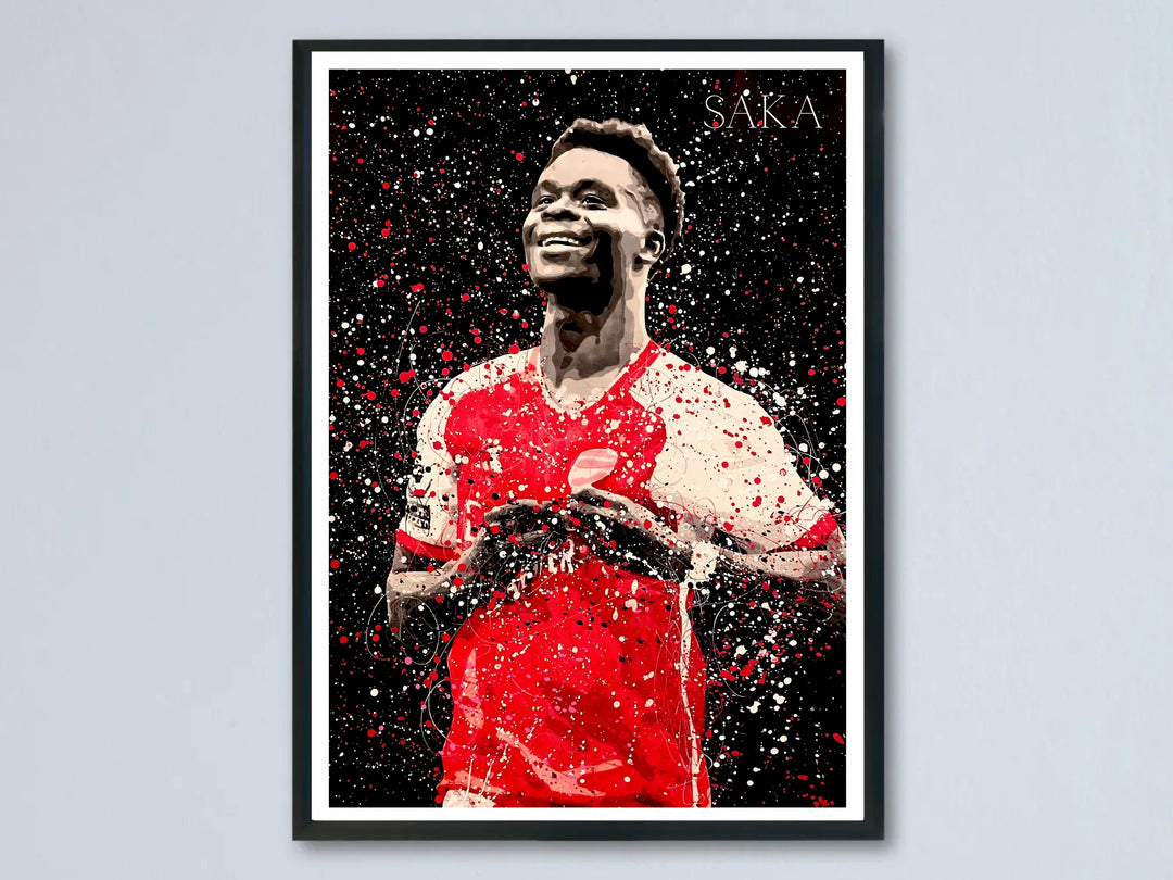 Splatter art poster of Bukayo Saka celebrating in his Arsenal FC kit, set against a black background with red and white paint-splash texture, a bold tribute to the North London club&
