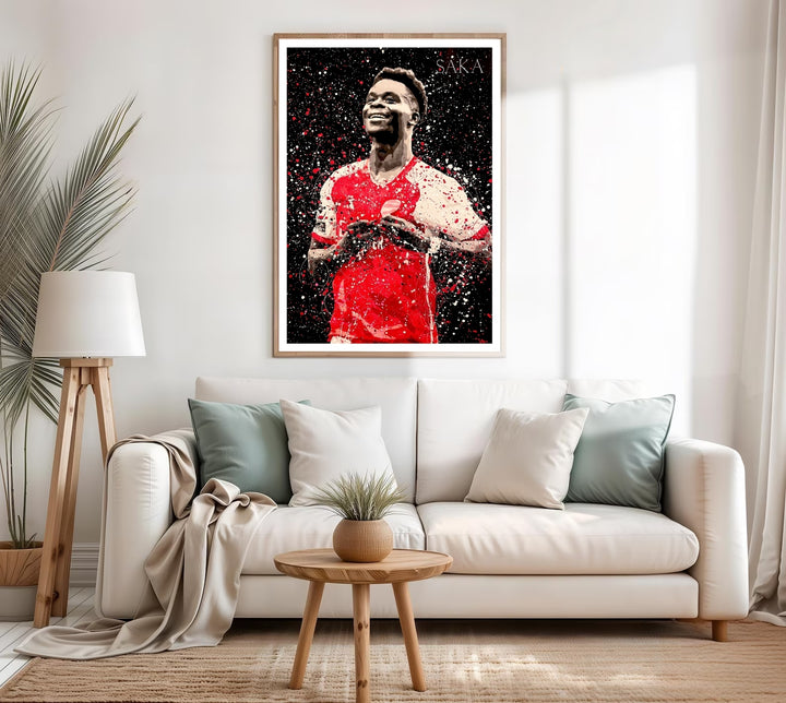 Arsenal FC splatter art print of Bukayo Saka mid-celebration, designed with expressive red and white paint texture on black, honoring the North London club&