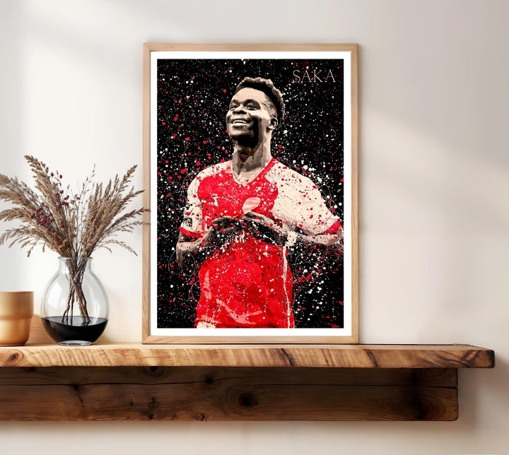 Portrait print of Bukayo Saka in Arsenal FC colors, illustrated in a dynamic splatter-paint style with fine ink line details, capturing the North London side&