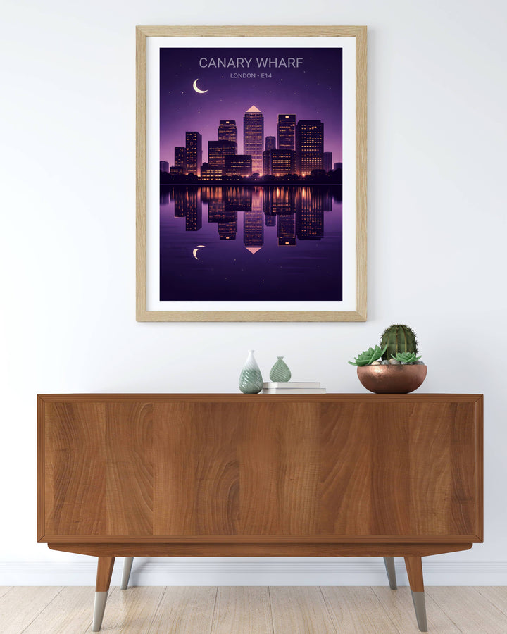 Framed artwork of Canary Wharf London E14 skyline at night on a wall above a wooden cabinet.