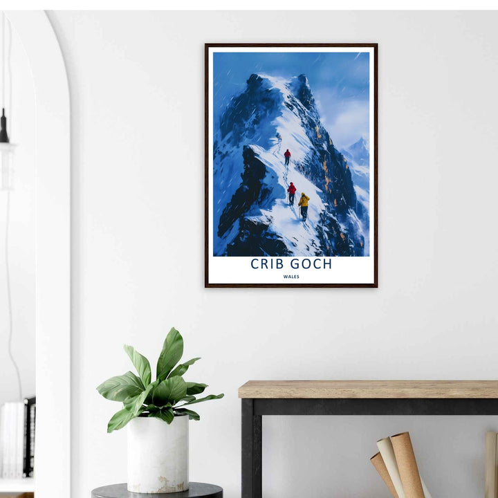 A colorful travel poster design of the scenic snowy Crib Goch mountain peak, available in a variety of presentation formats including unframed prints, canvas wall art, and framed finishes. The print highlights figures walking on a high mountain ridge.