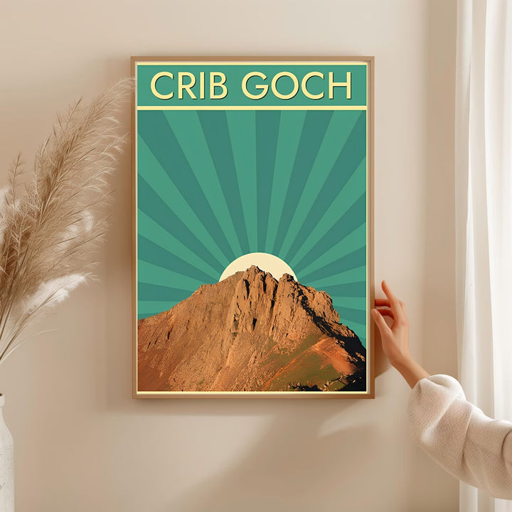 A vintage style art print of the Crib Goch mountain ridge in Snowdonia, Wales, offered as a canvas, an unframed poster, or custom framed wall decor. The scenic layout highlights a highly detailed rocky peak illuminated by golden sunlight against a vibrant teal art deco ray background design.