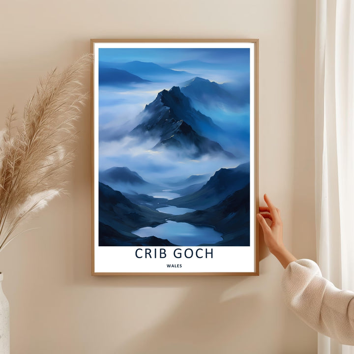 A vintage style landscape art print displaying the beautiful misty view of the Crib Goch mountain ridge, offered as a canvas, an unframed poster, or within a framed display. The layout highlights winding blue lakes nestled in a deep valley below clouds.