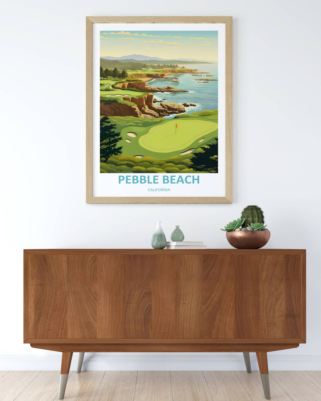 Framed retro golf artwork displaying an expansive coastal vista of Pebble Beach links with rich forest greens, sandy rock textures, and soft evening clouds in a modern black gallery frame.