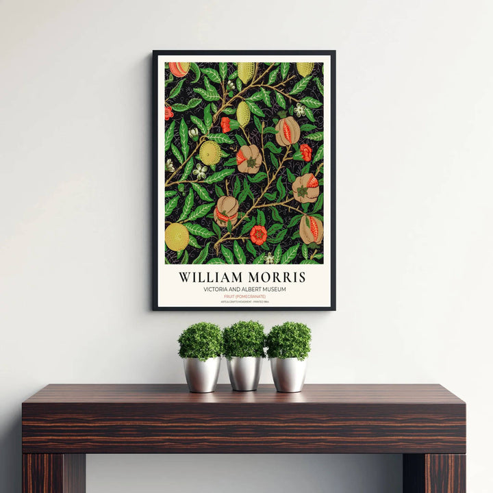 Elegant William Morris heritage wallpaper print showing dense foliage, woody branches, and fruit tendrils framed by a clean cream exhibition margin.