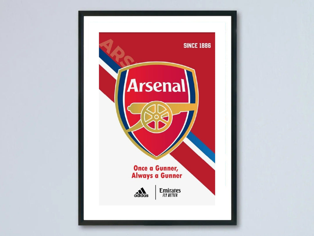 Framed Arsenal FC matchday kit poster featuring the red and gold club shield crest over a dynamic diagonal red, white, and navy stripe layout with Once a Gunner slogan inside a black frame.