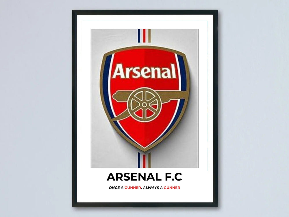 Modern Arsenal football club crest poster with a black gallery frame. Features the traditional red shield, gold cannon emblem, and bold typography stating Arsenal F.C. at the bottom border.