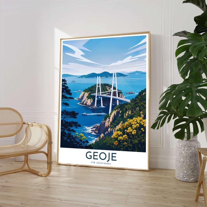 Scenic travel poster of Geoje, South Korea, featuring the grand Geoga Bridge crossing over deep blue sea channels lined with green forested cliffs and bright yellow wildflowers in the foreground. Offered by MapYourDreams, this artwork is available in flexible options including unframed paper, custom wooden frames, and gallery canvas wraps.
