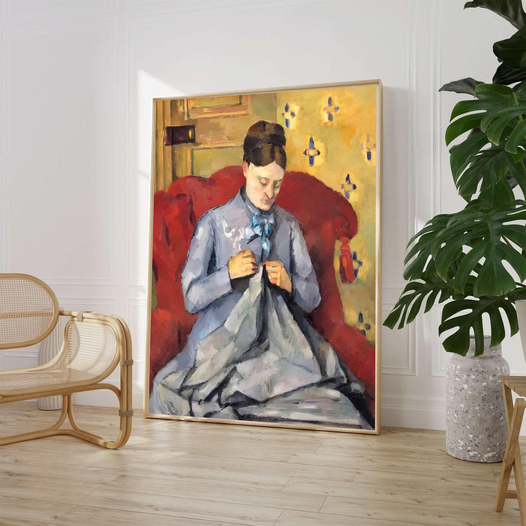 Paul Cezanne Madame Cezanne Sewing 1877 fine art poster created in Paris France depicting a woman in a blue dress sewing in a red armchair against yellow wallpaper. MapYourDreams provides custom framed wall art, unframed paper prints, and gallery stretched canvas wall decor options to elevate home decor.
