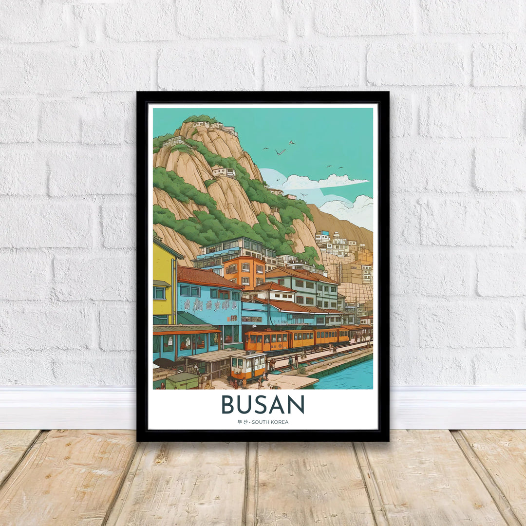 Retro-inspired travel poster of Busan, South Korea, presenting a bustling seaside neighborhood with pastel blue facades, yellow trains, and dramatic mountain background. Offered by MapYourDreams, this artwork is available in flexible options including unframed paper, custom wooden frames, and gallery canvas wraps.