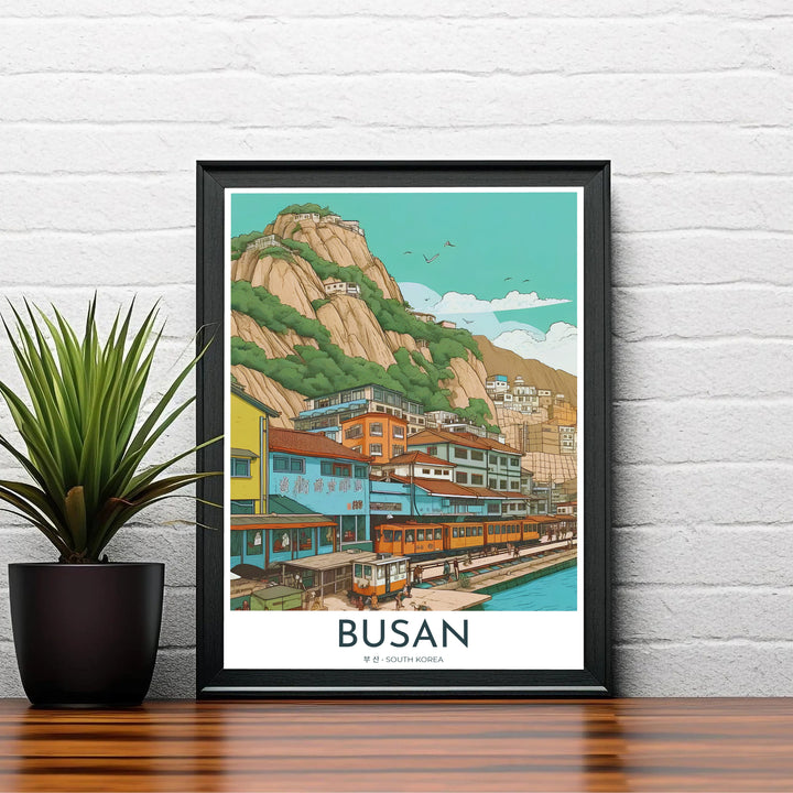 Charming Asian seaside village poster depicting Busan, South Korea, with terraced houses built along steep cliffs overlooking a tranquil blue bay and train tracks. Offered by MapYourDreams, this artwork is available in flexible options including unframed paper, custom wooden frames, and gallery canvas wraps.
