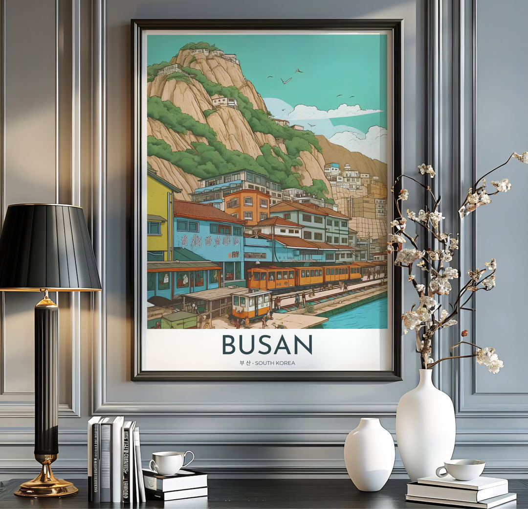 Modern vintage travel print with clean typography reading BUSAN SOUTH KOREA below a scenic illustration of a coastal village train line and rocky mountains. Offered by MapYourDreams, this artwork is available in flexible options including unframed paper, custom wooden frames, and gallery canvas wraps.