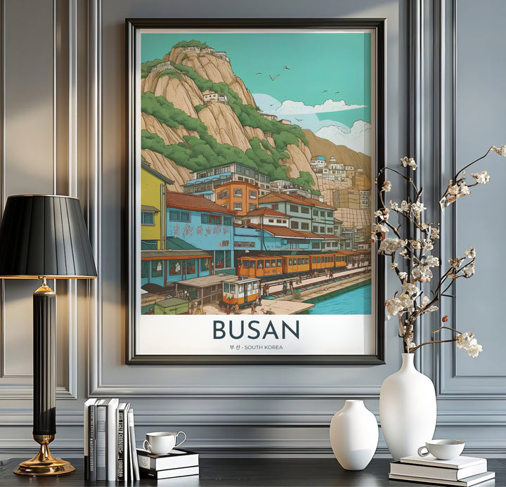 Modern vintage travel print with clean typography reading BUSAN SOUTH KOREA below a scenic illustration of a coastal village train line and rocky mountains. Offered by MapYourDreams, this artwork is available in flexible options including unframed paper, custom wooden frames, and gallery canvas wraps.