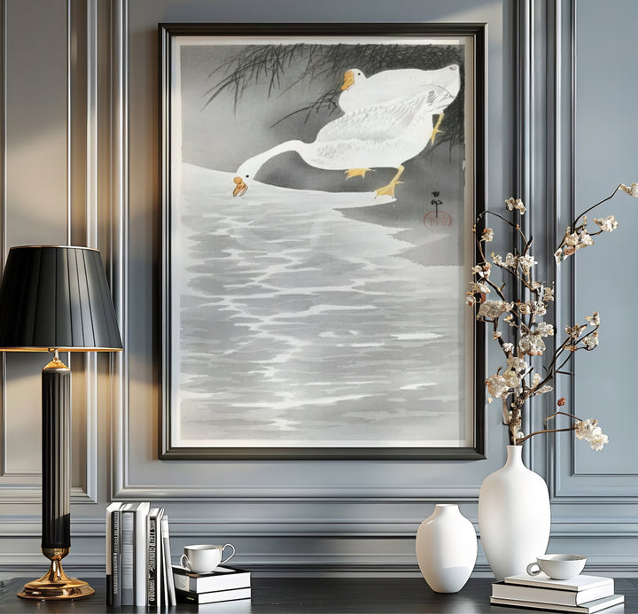 Two white geese drinking from a water bank by artist Ohara Koson inspired by Japanese tea house gardens in Kyoto. MapYourDreams offers versatile framed, unframed, and canvas print wall decor formats.