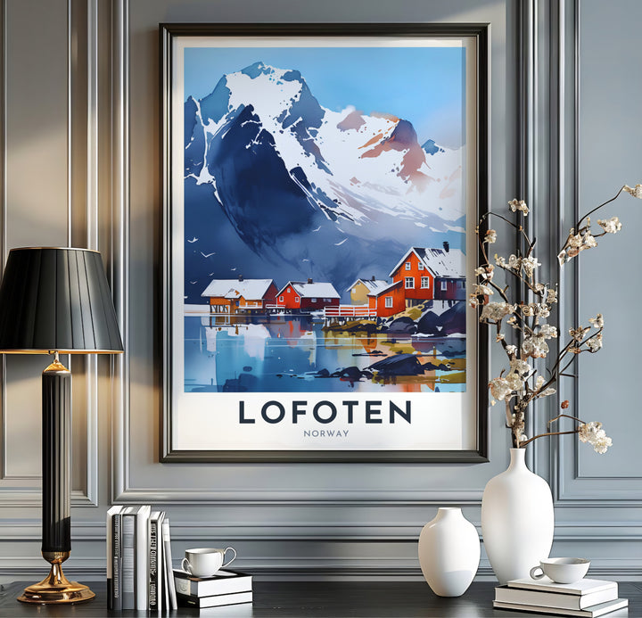 Breathtaking view of towering snowy peaks and red fishing cabins in Lofoten Norway reflecting across smooth coastal water. This travel landscape piece is offered across multiple formats including custom framed prints, premium canvas stretched artwork, and classic unframed poster options.