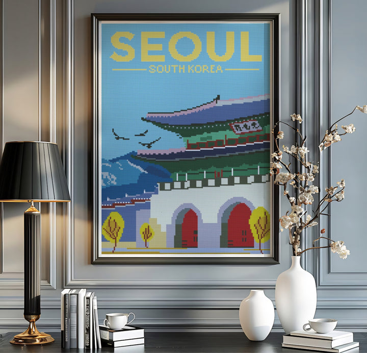 Textured cross-stitch poster with bold yellow typography reading SEOUL SOUTH KOREA woven into a clear blue sky background above Gwanghwamun Gate and distant mountain ranges. Offered by MapYourDreams, this artwork is available in flexible options including unframed paper, custom wooden frames, and gallery canvas wraps.