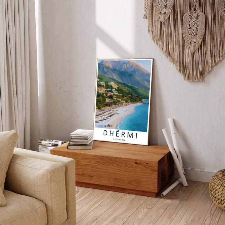 Thatched sunshades and loungers rest on the white pebbles of Dhërmi Beach, framed by blue mountains and clear skies in this fine photograph. Offered by MapYourDreams in custom choices such as unframed paper, wood-framed options, and gallery-style canvas.