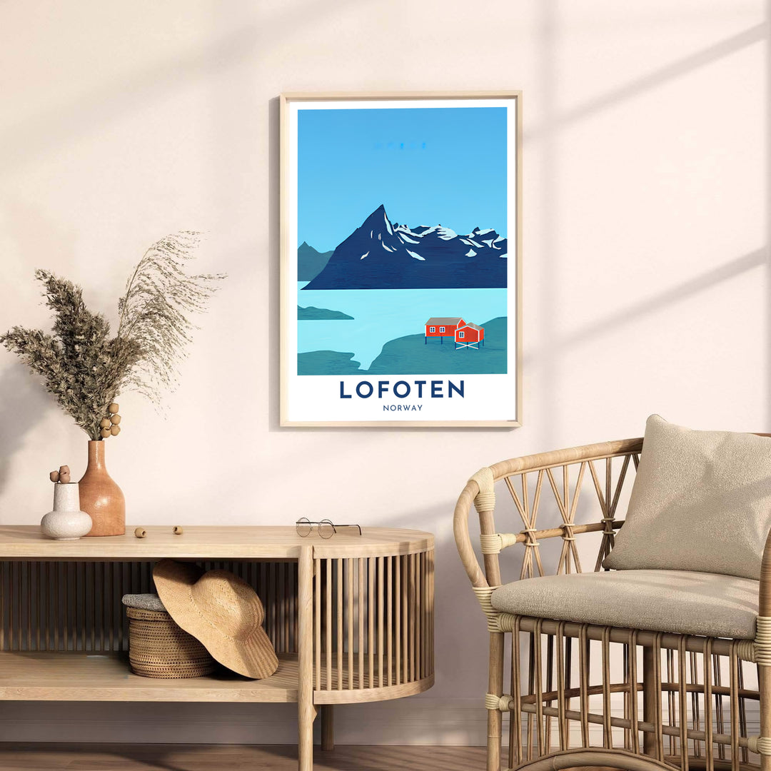 Scenic graphic print of Lofoten Norway with a prominent snow-dusted peak towering over red waterfront cottages. Upgrade your room interior with this travel artwork available across physical formats such as unframed paper prints, protective framed designs, and gallery wrap canvas prints.