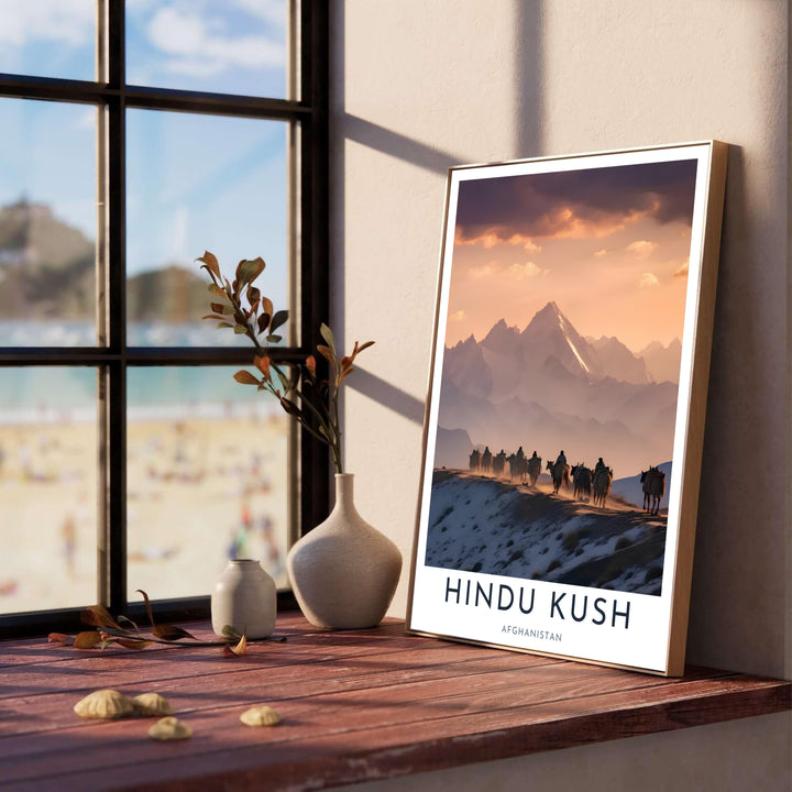 Dramatic sunset mountain poster of the Afghanistan Hindu Kush range with nomadic riders traveling across a snowy slope, offered by MapYourDreams as an unframed fine art poster, stretched canvas print wall art, or custom framed print in retro black and natural wood moulding for home libraries.