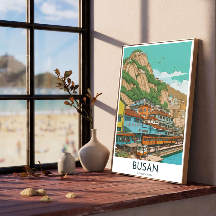 Colorful coastal village wall art of Busan, South Korea, showing vintage beach trains, terraced seaside homes, and soaring granite peaks against a bright mint sky. Offered by MapYourDreams, this artwork is available in flexible options including unframed paper, custom wooden frames, and gallery canvas wraps.