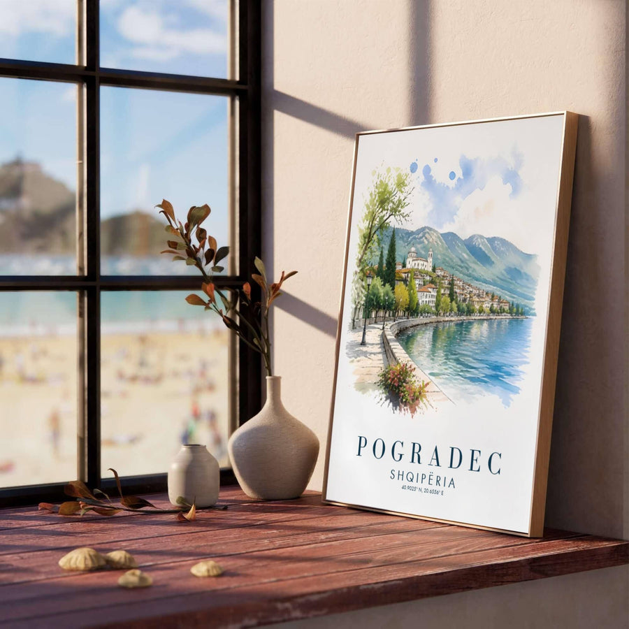 Soft blue and cerulean watercolor washes illustrate the serene shores of Lake Ohrid in Pogradec, creating a classic European travel poster for living rooms. Offered in versatile formats including unframed art paper, custom wood framing, and stretched canvas wraps to elevate your space.