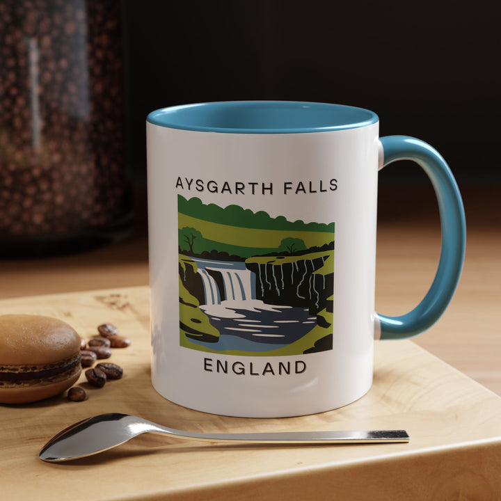 A captivating Aysgarth Falls England mug featuring the stunning waterfalls surrounded by lush greenery. This mug is perfect for enjoying hot beverages. Dishwasher safe and microwave safe, it is a thoughtful gift for those who love British landscapes.