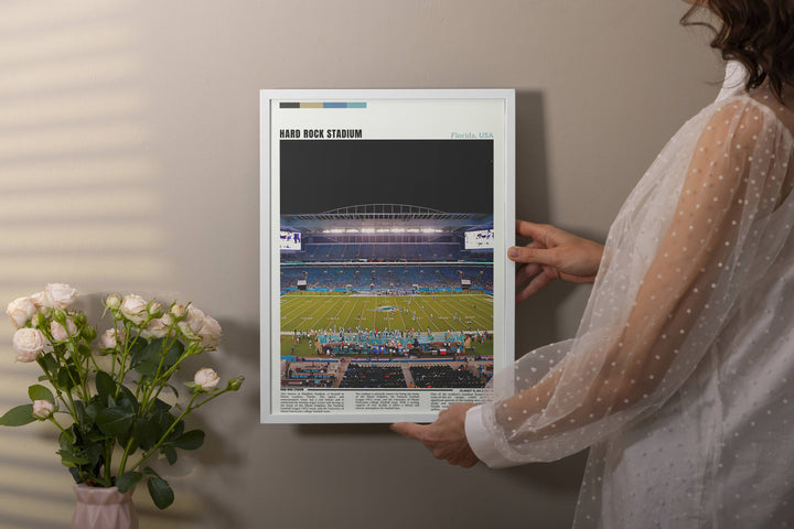 a woman holding a framed photo of a football stadium