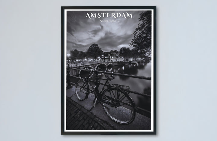 Amsterdam night canal poster capturing historic gabled houses and illuminated bridge lights under a cloudy night sky, offered by MapYourDreams with catalog selections for an unframed matte paper poster, a durable gallery wrapped canvas, or a custom frame for bedroom and hallway wall styling.