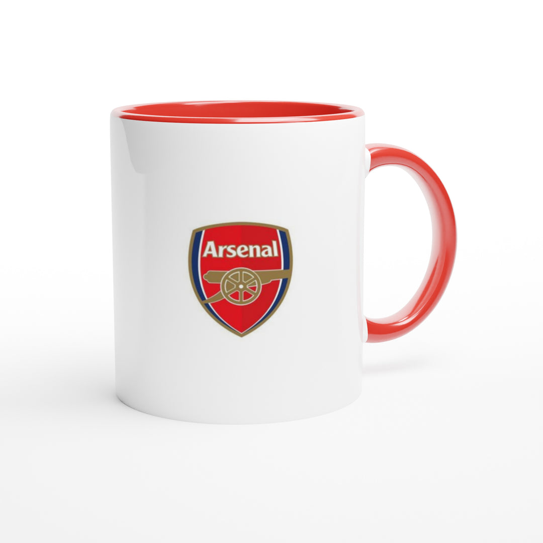 A glossy white Arsenal cup with a vibrant red interior lining sitting on a checkered table mat next to matching home decor utensils and a green houseplant.