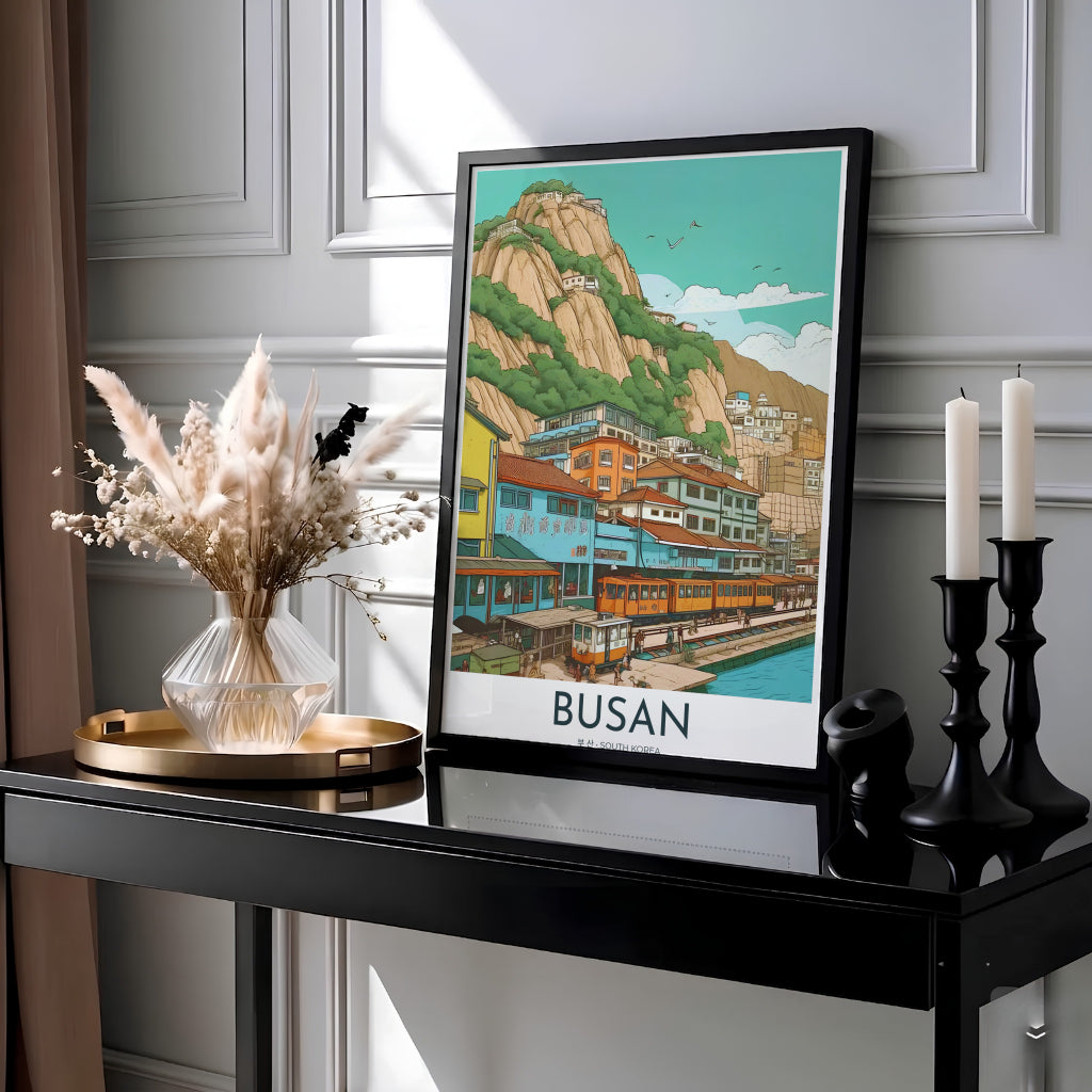 Serene Asian landscape print capturing a coastal railway line in Busan, South Korea, with pastel blue, yellow, and orange buildings cascading down a green hillside to the sea. Offered by MapYourDreams, this artwork is available in flexible options including unframed paper, custom wooden frames, and gallery canvas wraps.