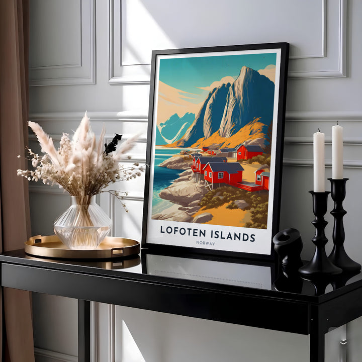 Picturesque coastal view of Lofoten Islands Norway with steep granite cliffs rising above red shoreline rorbuer cabins and blue waters. This destination wall art print is crafted for living rooms and office spaces, with customizable choices as a ready to hang framed poster, stretched canvas wrap, or classic unframed art paper print.