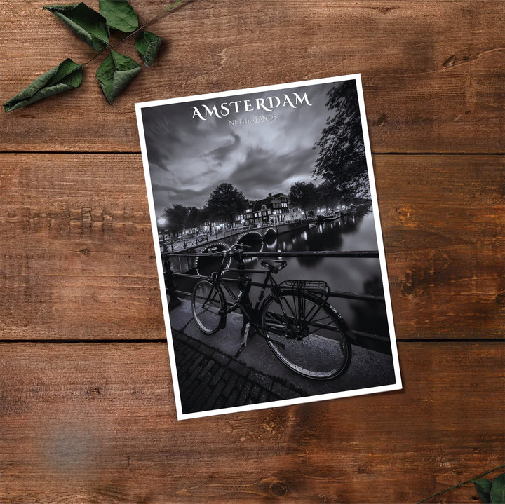 Cinematic black and white travel print of historic Amsterdam canal houses paired with a parked bike and bridge reflections, available at MapYourDreams where you can select from unframed paper prints, gallery canvas, or custom framed wall art options for modern interior spaces.