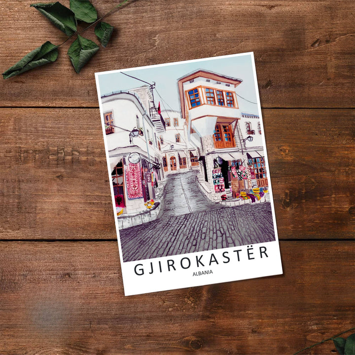 Fine art travel poster showing Gjirokastra Old Bazaar with sunny skies, timber windows, and traditional woven carpets on display. Choose from flexible display setups including unframed archival paper, wooden frames, or wrapped canvas formats.