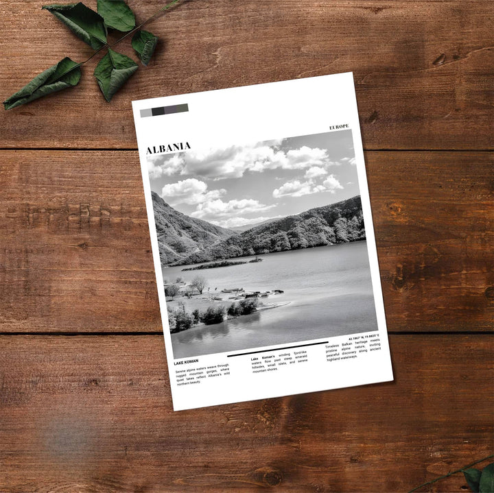 Fine art travel poster showing Lake Koman with cloudy skies, forested hills, and serene waters displayed across an inviting horizontal layout. Choose from flexible display setups including unframed archival paper, wooden frames, or wrapped canvas formats.
