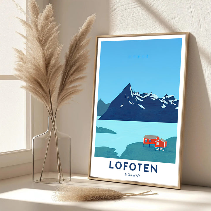 Coastal mountain poster depicting Lofoten in Norway with red rorbuer cabins and calm turquoise waters under a vast sky. Bring Scandinavian style into your home with this print available in classic unframed paper, gallery wrapped canvas panels, or fully assembled framed displays.