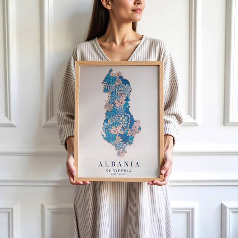 Crisp cartographic artwork showing the country map of Albania in navy blue and blush pink floral linework with modern serif country lettering. Offered by MapYourDreams, this artwork is available in flexible options including unframed paper, custom wooden frames, and gallery canvas wraps.