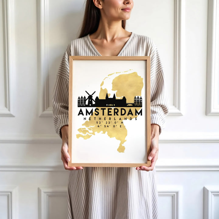 Sophisticated European cartography print displaying a golden Netherlands outline with black Amsterdam skyline elements and coordinates, presented by MapYourDreams where customers can choose from unframed paper posters, ready-to-hang canvas, or custom framed wall decor options.