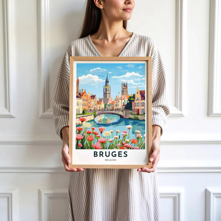 Charming floral city decor displaying pink wildflowers, an arched bridge, and step-gabled buildings in Bruges, Belgium. Available in multiple presentation styles such as unframed paper prints, custom framed posters, and gallery stretched canvas.