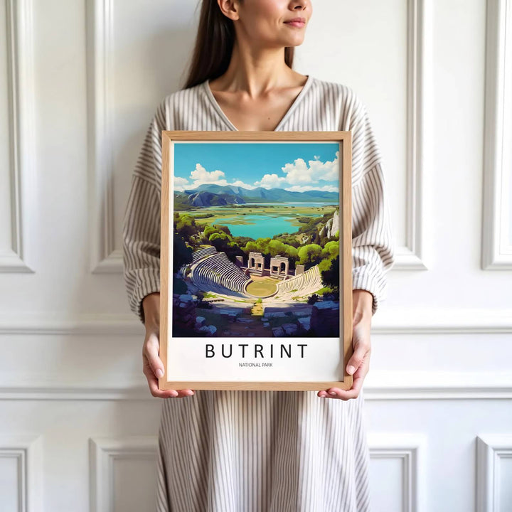 Crisp graphic artwork showing the ancient amphitheater of Butrint Albania with stone seating, arched stage, and distant blue mountains behind. Offered by MapYourDreams, this artwork is available in flexible options including unframed paper, custom wooden frames, and gallery canvas wraps.